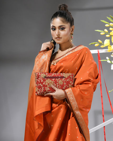 Close-up of silver zari butti on orange pure silk saree.